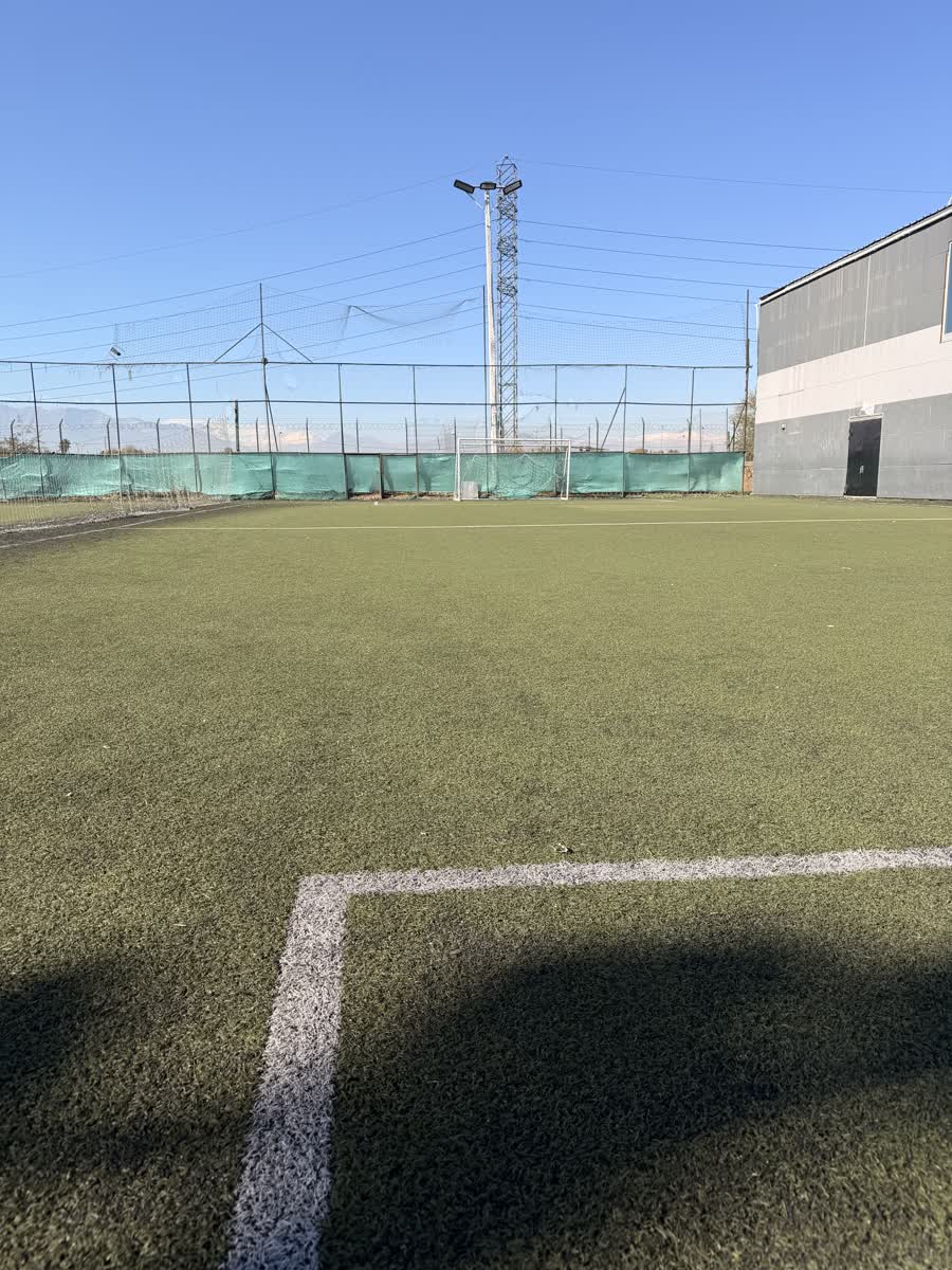 Esquina de la cancha con la fachada del complejo y torres de iluminación